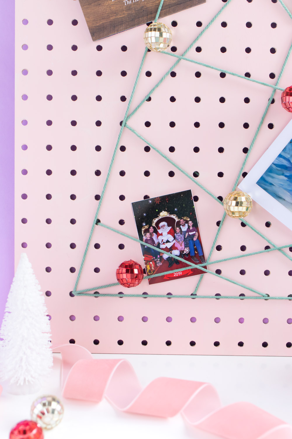 DIY Holiday Pegboard Card Holder // Turn a slab of pegboard into a fun Christmas tree card display inspired by string art! Display your holiday cards in a unique way with this DIY Christmas decor idea #christmasdiy #christmascard #christmasdecor #christmasstorage #pegboard #papercrafts #stringart #holidaystorage #cardstorage